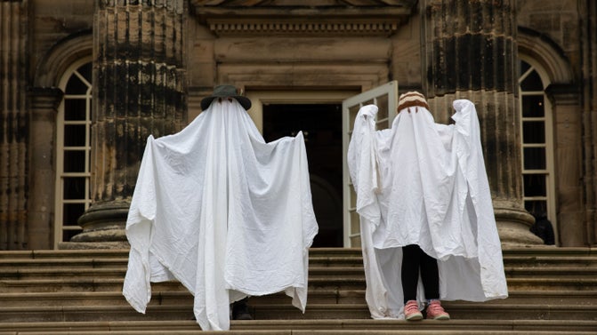 Children standing on the south steps at Seaton Delaval Hall. They are in ghostly fancy dress with their bodies obscured completely by white sheets, which just have cuts outs for eyes